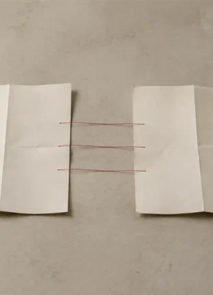 Redesign website without losing SEO: two folded paper maps side by side on a desk, matching points joined by scarlet thread