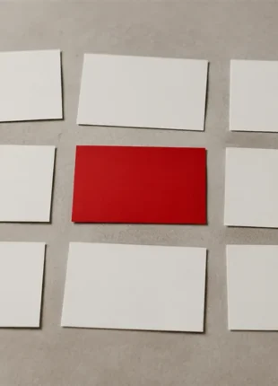 Nine blank paper cards laid out in a grid on a desk with one scarlet card among them, an illustration of the signs your website needs a redesign